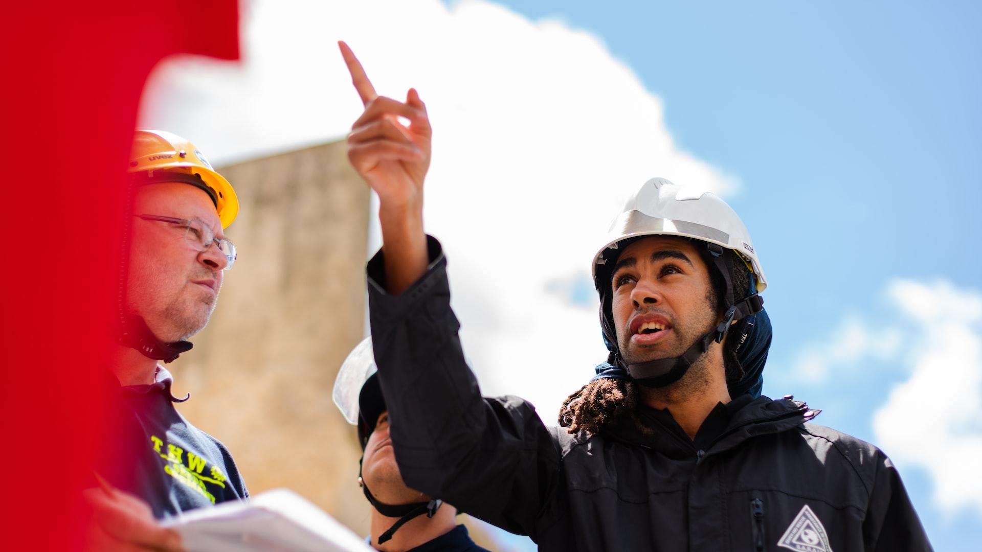 man in black jacket wearing yellow hard hat